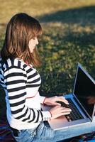 jovem adolescente trabalha no laptop ao ar livre foto