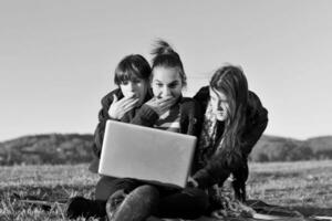 grupo de adolescentes trabalhando no laptop ao ar livre foto