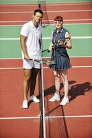 casal jovem feliz joga tênis ao ar livre foto