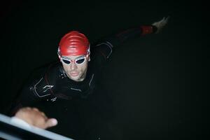 nadador de triatleta autêntico tendo uma pausa durante o treinamento duro na noite foto