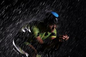 atleta de triatlo andando de bicicleta rápido na noite chuvosa foto