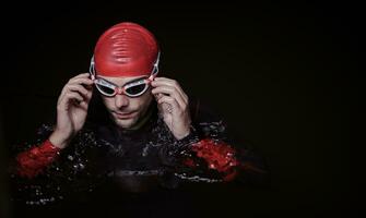 nadador de triatleta autêntico tendo uma pausa durante o treinamento duro na noite foto