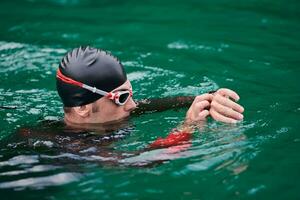 atleta de triatlo nadando no lago configuração smartwatch foto