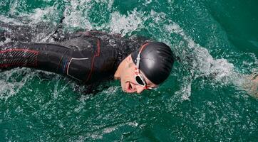 atleta de triatlo nadando no lago vestindo roupa de mergulho foto