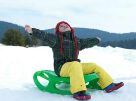 menino feliz se diverte nas férias de inverno na neve fresca foto