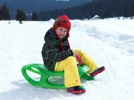 menino feliz se diverte nas férias de inverno na neve fresca foto