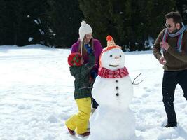 família feliz fazendo boneco de neve foto