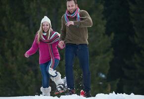 casal se divertindo e andando com sapatos de neve foto