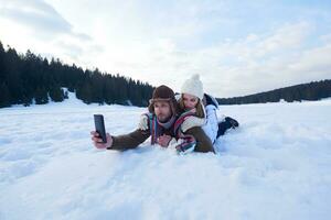 casal romântico se diverte na neve fresca e tirando selfie foto