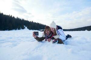 casal romântico se diverte na neve fresca e tirando selfie foto