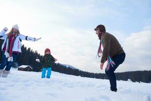 família feliz jogando juntos na neve no inverno foto