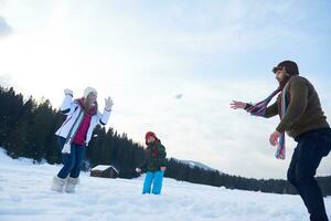 família feliz jogando juntos na neve no inverno foto