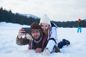 casal romântico se diverte na neve fresca e tirando selfie foto