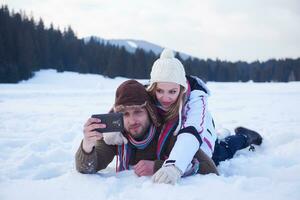 casal romântico se diverte na neve fresca e tirando selfie foto