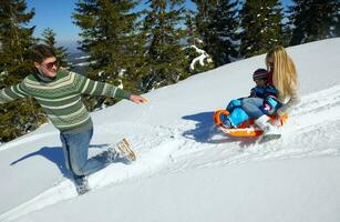 família se divertindo na neve fresca no inverno foto