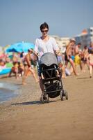 mãe andando na praia e empurra o carrinho de bebê foto