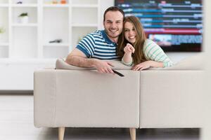 jovem casal no sofá assistindo televisão foto