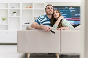 jovem casal no sofá assistindo televisão foto