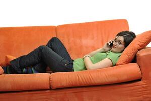 jovem feliz relaxa no sofá laranja foto