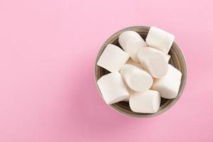 marshmallow em uma tigela em fundo rosa pastel foto