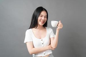 jovem mulher asiática com um rosto feliz e uma mão segurando uma xícara de café foto