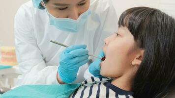 ásia fêmea dentista examinar jovem menina paciente dentes e dor de dente estomatologia dentro dental clínica, bem estar higiene Verificações, e profissional ortodôntico cuidados de saúde trabalhos dentro médico escritório hospital. foto