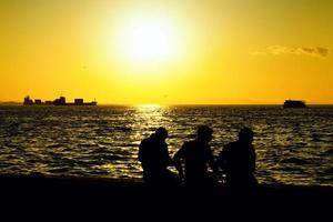 silhueta de pessoas e o mar ao pôr do sol foto