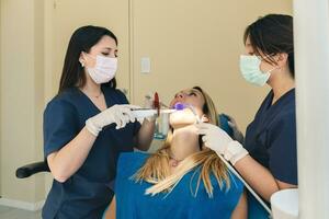 dentista e assistente usando dental uv cura luz foto