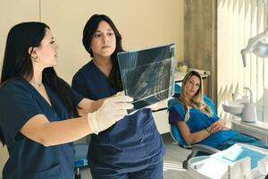 médico equipe examinando pacientes raio X imagem dentro dental clínica. foto