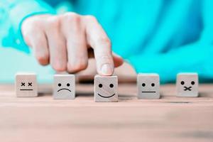 empresário escolhe um rosto de ícones emoticon feliz no bloco de madeira. foto