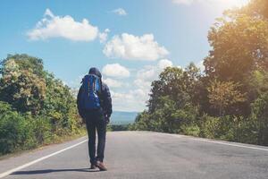 homem alpinista andando na estrada rural. conceito de turismo de férias. foto