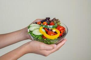 linda mulher segurando uma tigela de salada vegetariana fresca foto