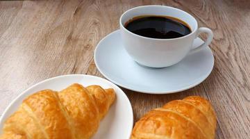 xícara de café quente e croissant lanche da manhã foto