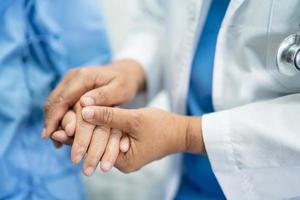 segurando a mão de uma paciente idosa asiática com amor foto
