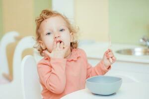 pequeno bebê come massa dentro a crianças cozinha foto