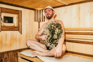 uma homem com uma vassoura dentro dele mão é relaxante dentro a sauna foto