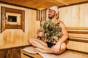 uma homem com uma vassoura dentro dele mão é relaxante dentro a sauna foto