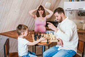 feliz família jogando xadrez dentro a cozinha foto