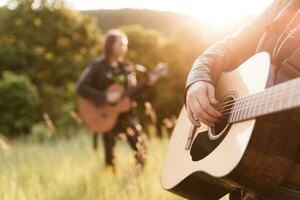 mulher e homem jogando acústico guitarra dentro natureza às pôr do sol foto