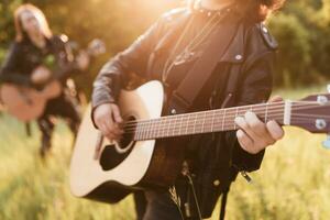 mulher e homem jogando acústico guitarra dentro natureza às pôr do sol foto