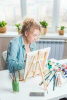 lindo menina artista tintas em tela de pintura às casa foto