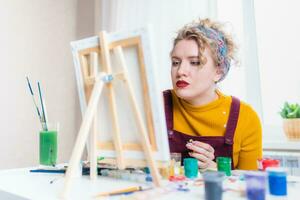 lindo mulher artista tintas em tela de pintura às casa foto
