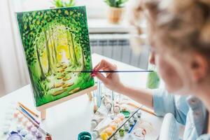 lindo menina artista tintas em tela de pintura às casa foto