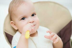 bebê segurando uma colher dentro dele boca e risos foto