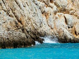 rochoso falésias e surpreendente azul mar - onda falhando em a penhasco foto