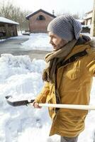 jovem homem pá neve perto uma Fazenda foto