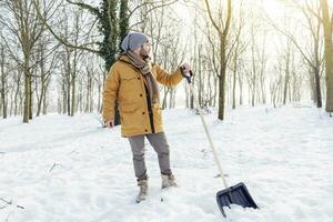 jovem homem pá neve perto uma pequeno madeira foto