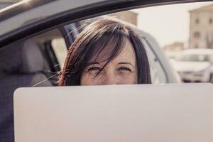 o negócio mulher trabalhando em a computador dentro uma estacionamento foto