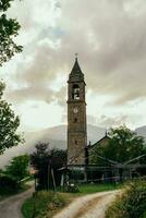 antigo Sino torre dentro uma medieval Vila cercado de colinas às pôr do sol foto