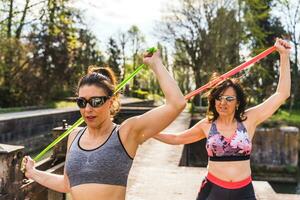 lindo meio envelhecido mulheres fazendo exercícios ao ar livre com uma resistência banda foto